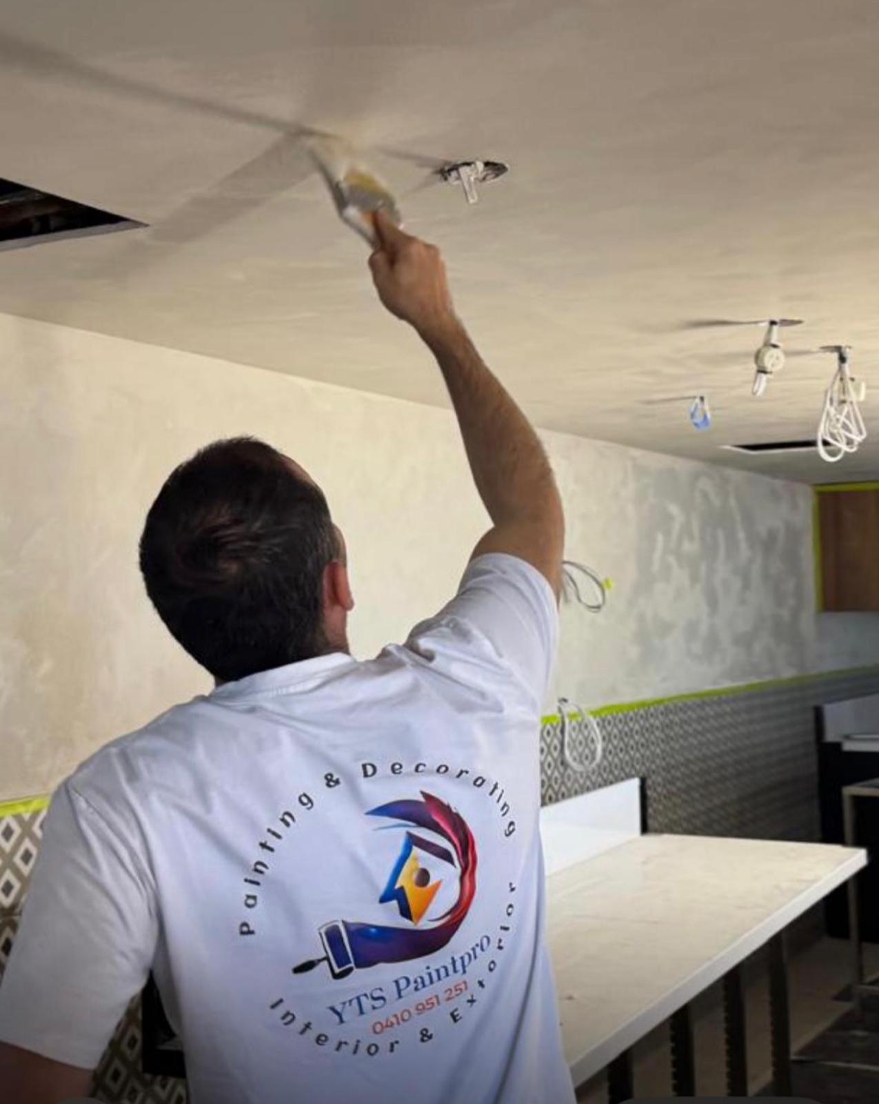 A YTS PaintPro painter cutting in a ceiling by hand during an interior fit-out